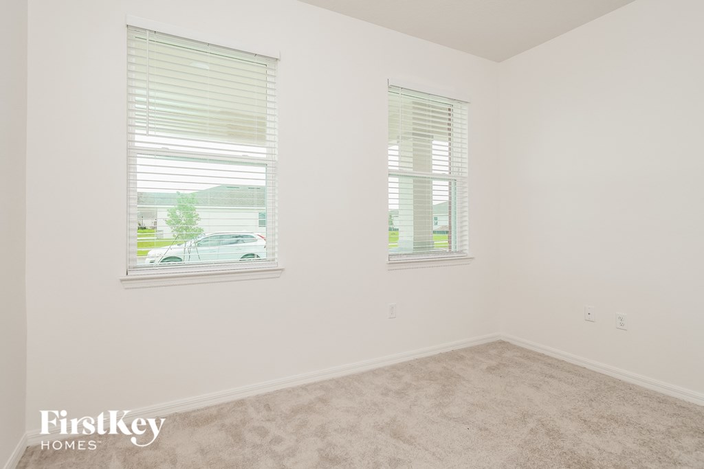 a bedroom with two windows and a carpeted floor