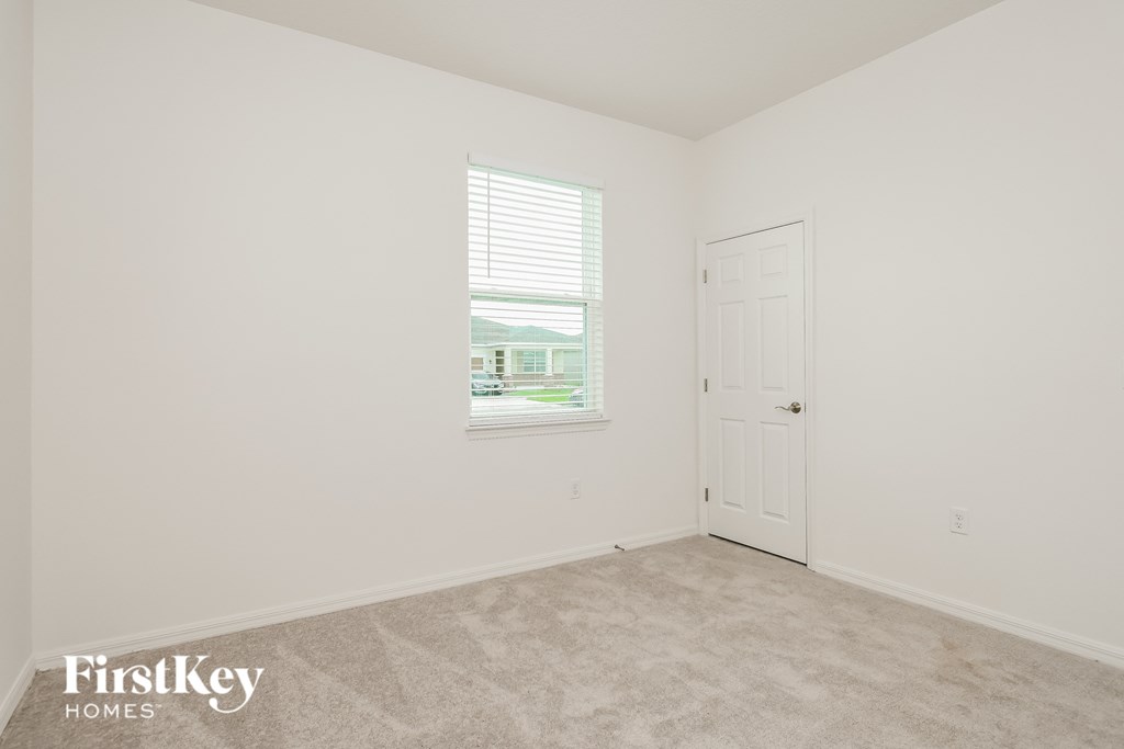 a bedroom with white walls and a door and a window