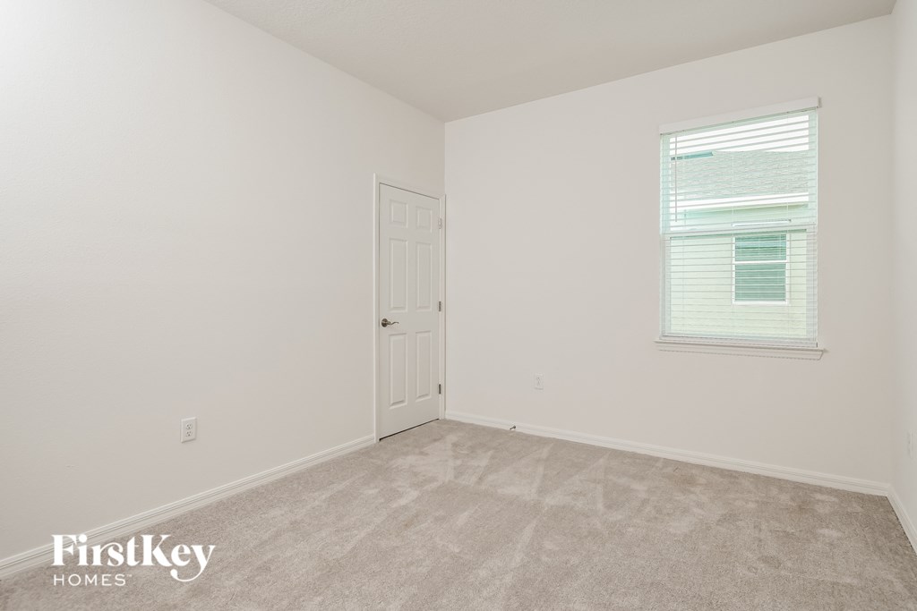 a bedroom with white walls and carpet and a door