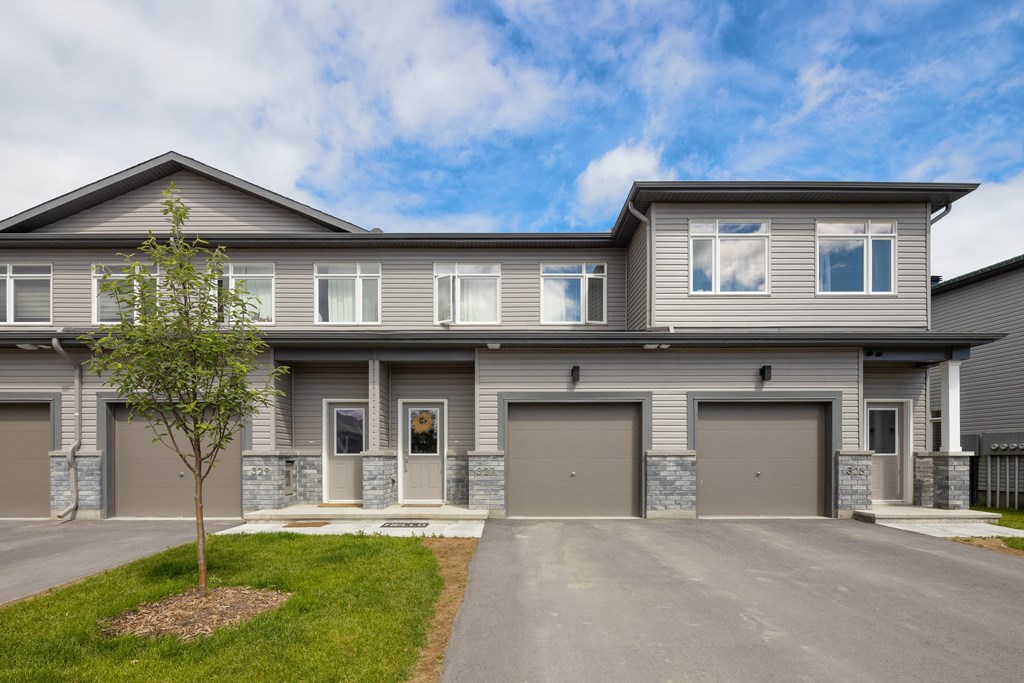 the front of a gray house with two garage doors