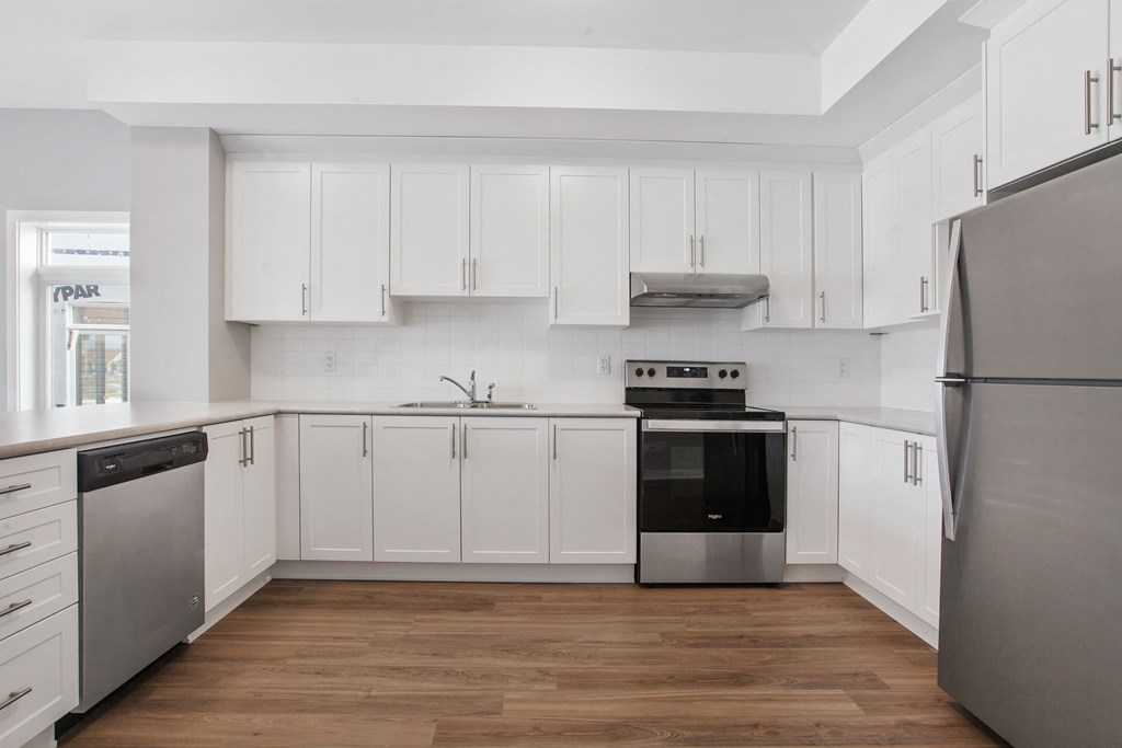a white kitchen with white cabinets and stainless steel appliances