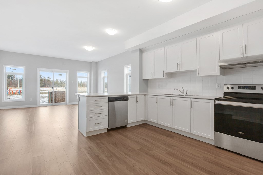 an empty kitchen with white cabinets and stainless steel appliances