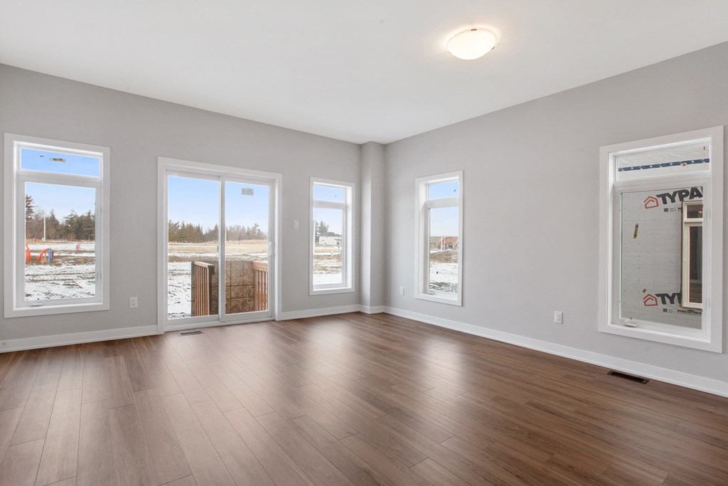 the living room of an empty house with wood floors and windows