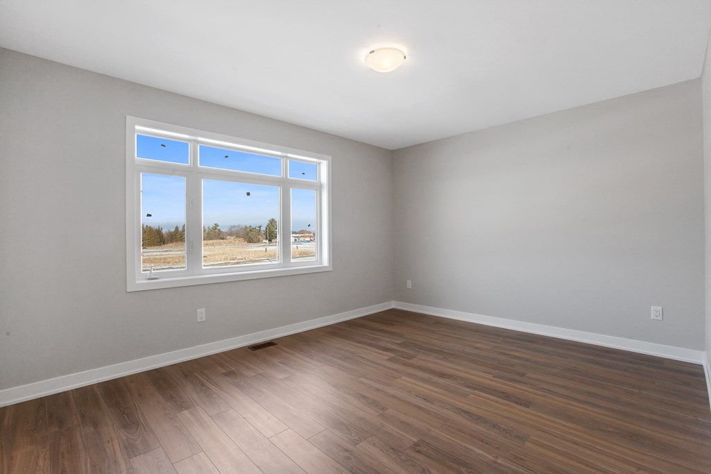 an empty living room with wood floors and a window