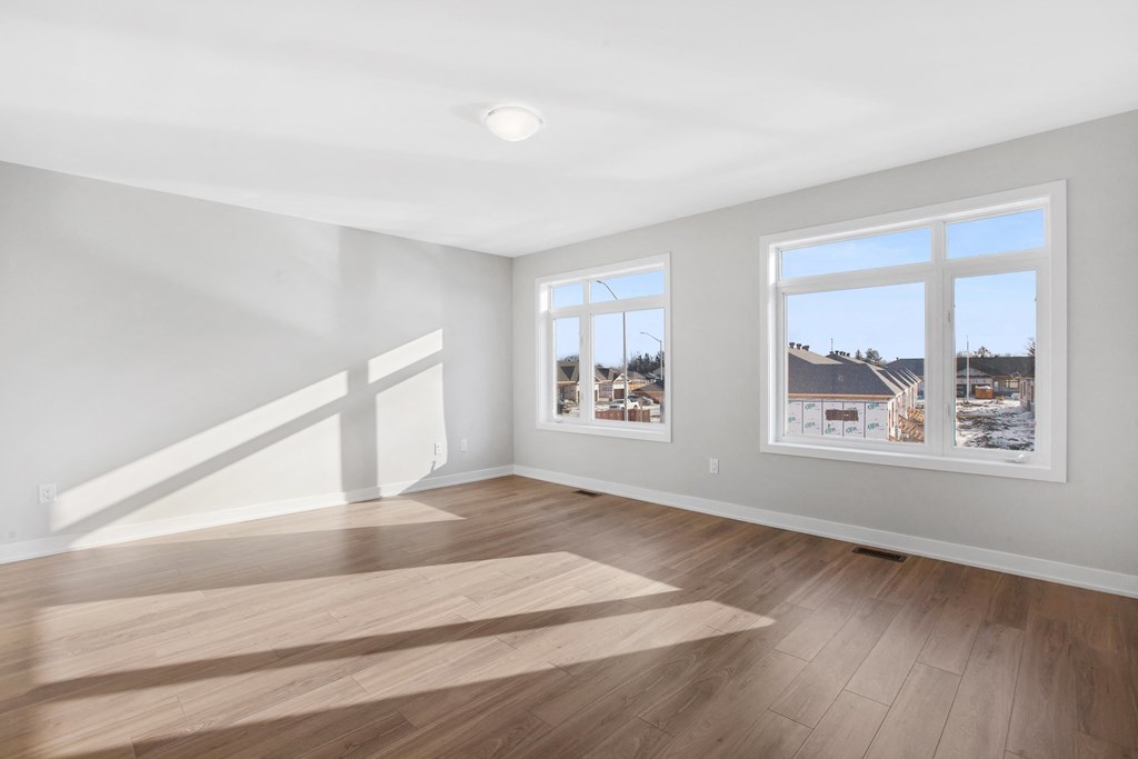 an empty living room with hardwood floors and two windows