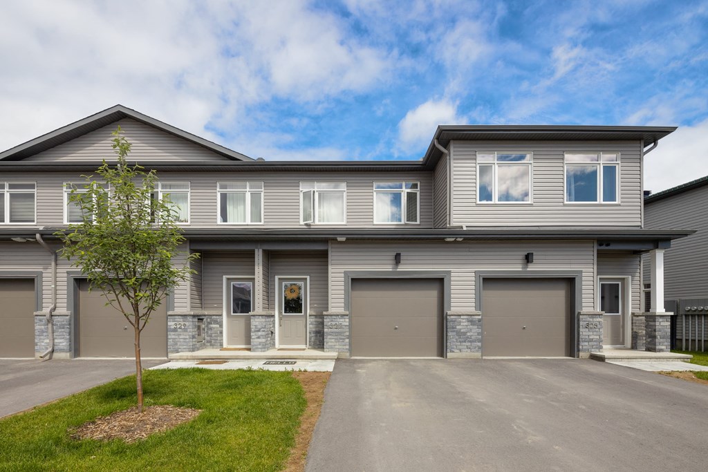the front of a gray house with two garage doors