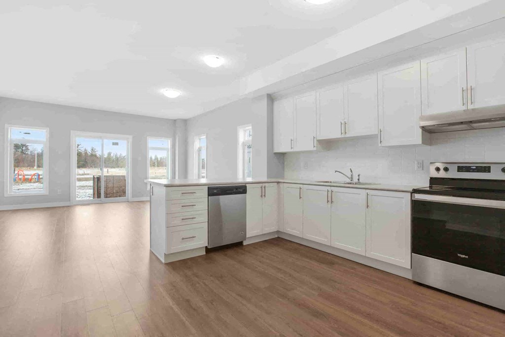 an empty kitchen with white cabinets and stainless steel appliances
