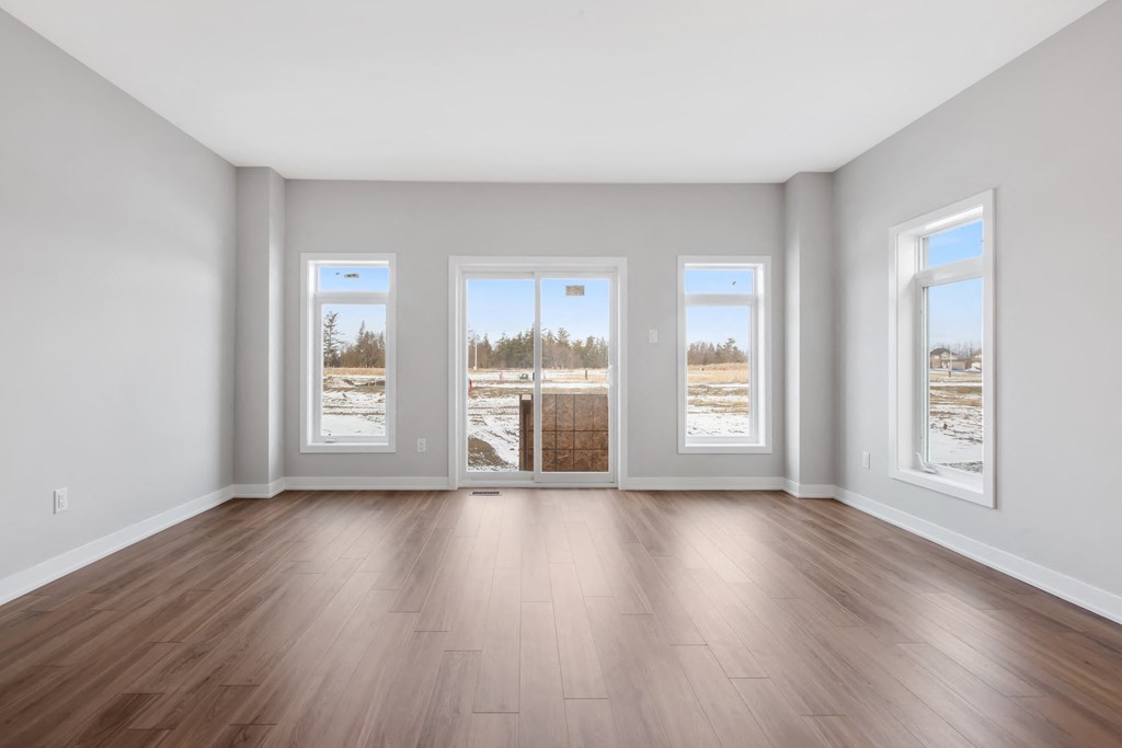 the living room of an empty house with wood floors and windows