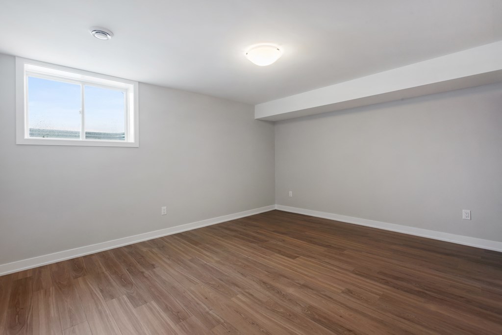 an empty room with wooden floors and a window
