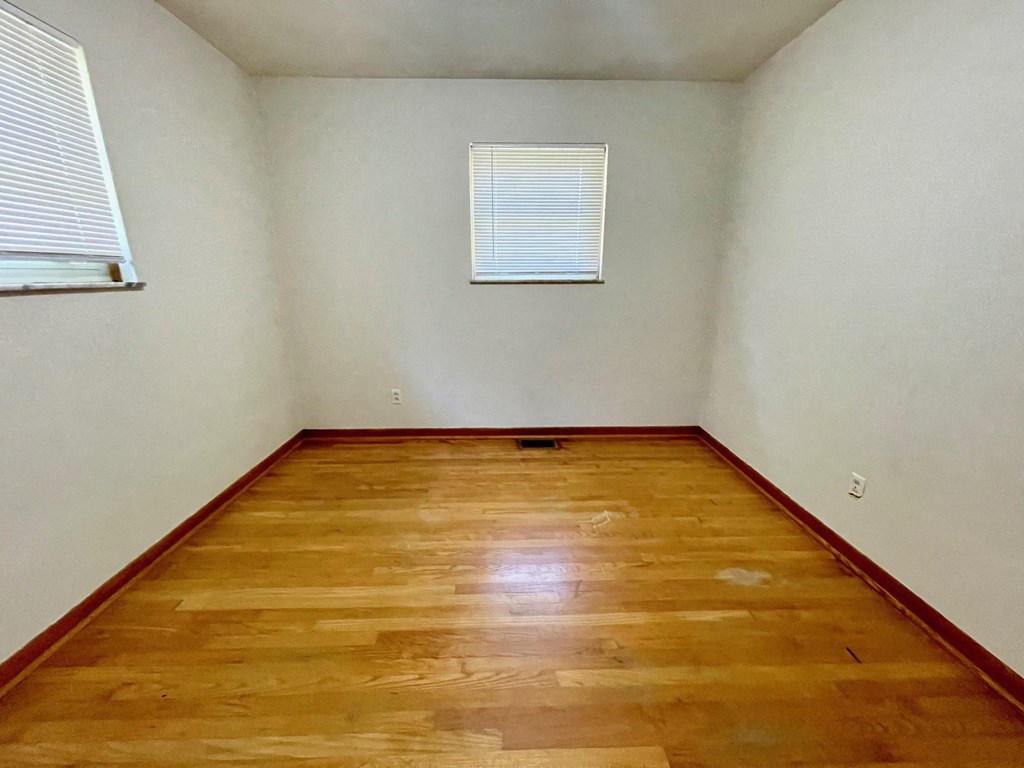 an empty room with wooden floors and a window