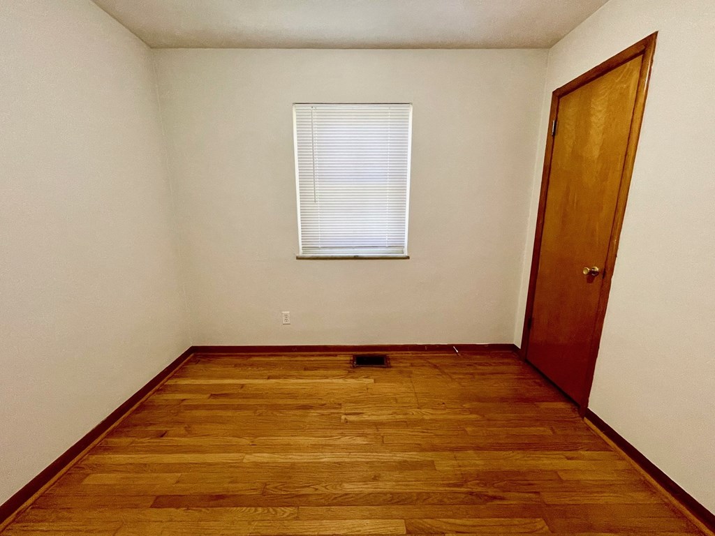 an empty room with a window and wooden floors