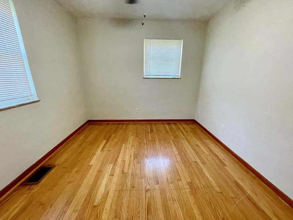 a room with wood floors and white walls and a window
