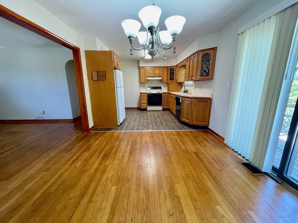 a kitchen and living room with wood floors and wooden cabinets