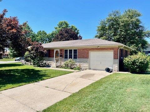 a small brick house with a driveway and a garage door