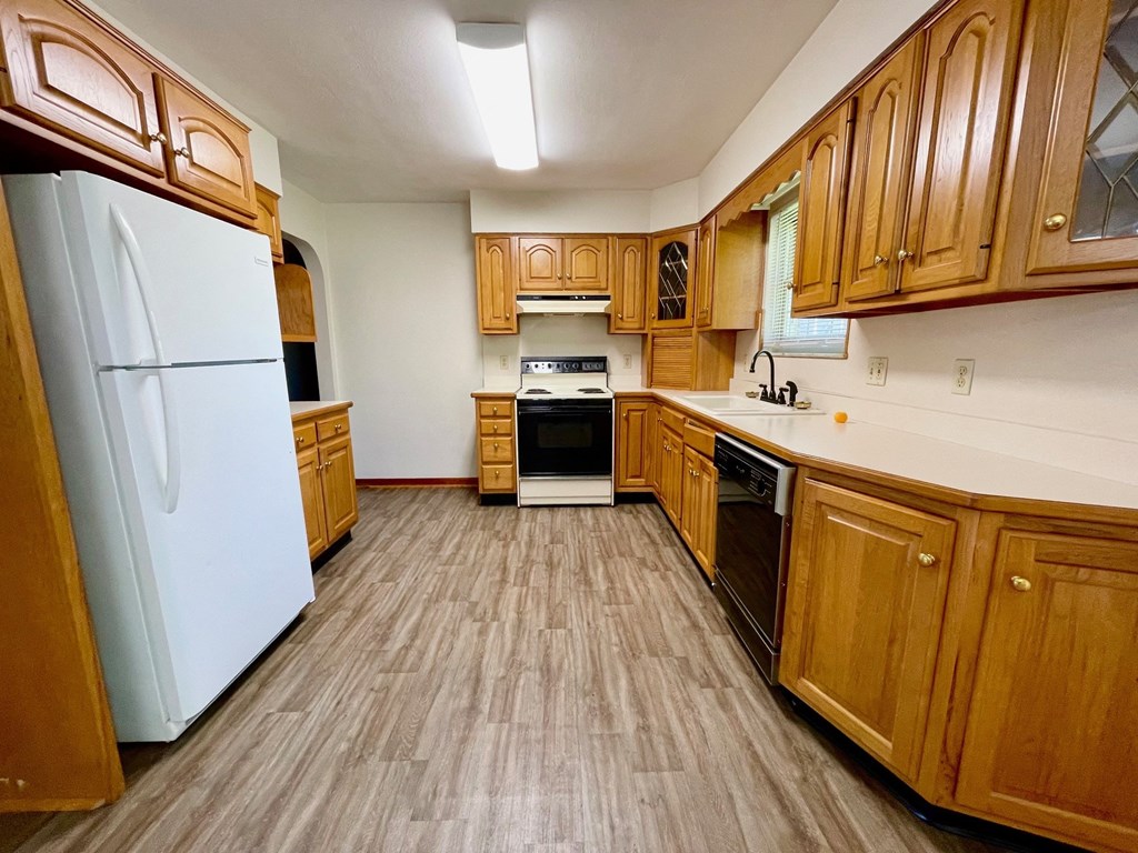a kitchen with wood floors and wooden cabinets and a white refrigerator