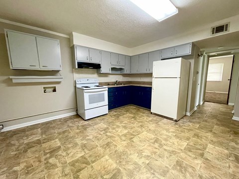 an empty kitchen with white appliances and white cabinets