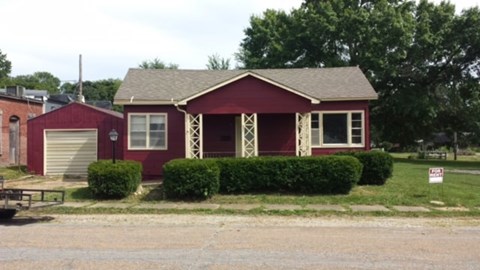 A red house with a white trim and a sign in front of it.