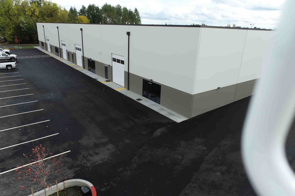 a large white building with a parking lot and trees