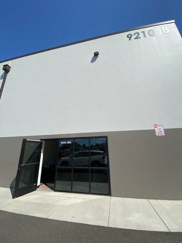 the front of a building with a door and a car in it