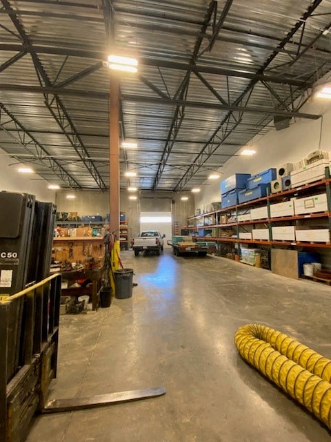 a large warehouse with rows of shelves and a yellow hose