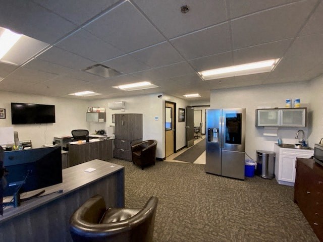 a room with a desk and a refrigerator in it