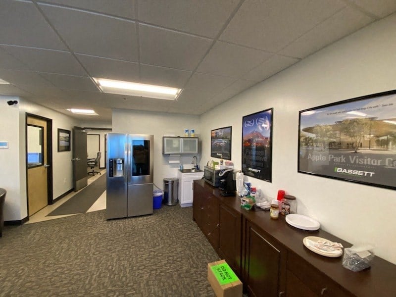 a room with a kitchen and a refrigerator and a bulletin board