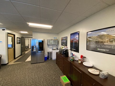 a room with a kitchen and a refrigerator and a bulletin board