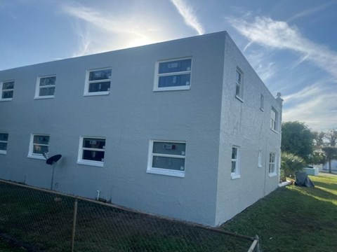 A white building with multiple windows and a fence in front.