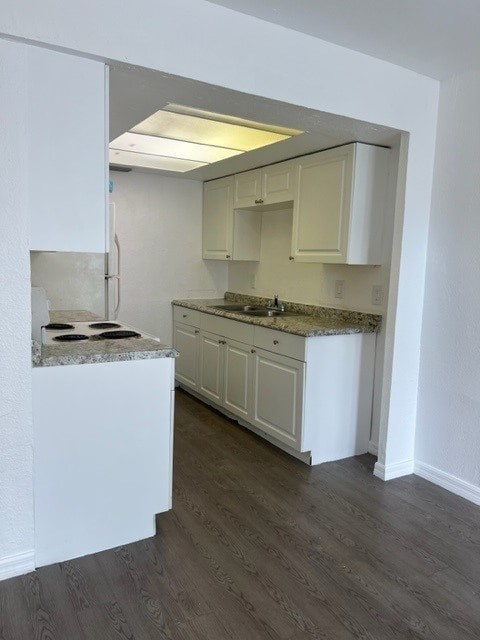 A kitchen with white cabinets and a marble countertop.