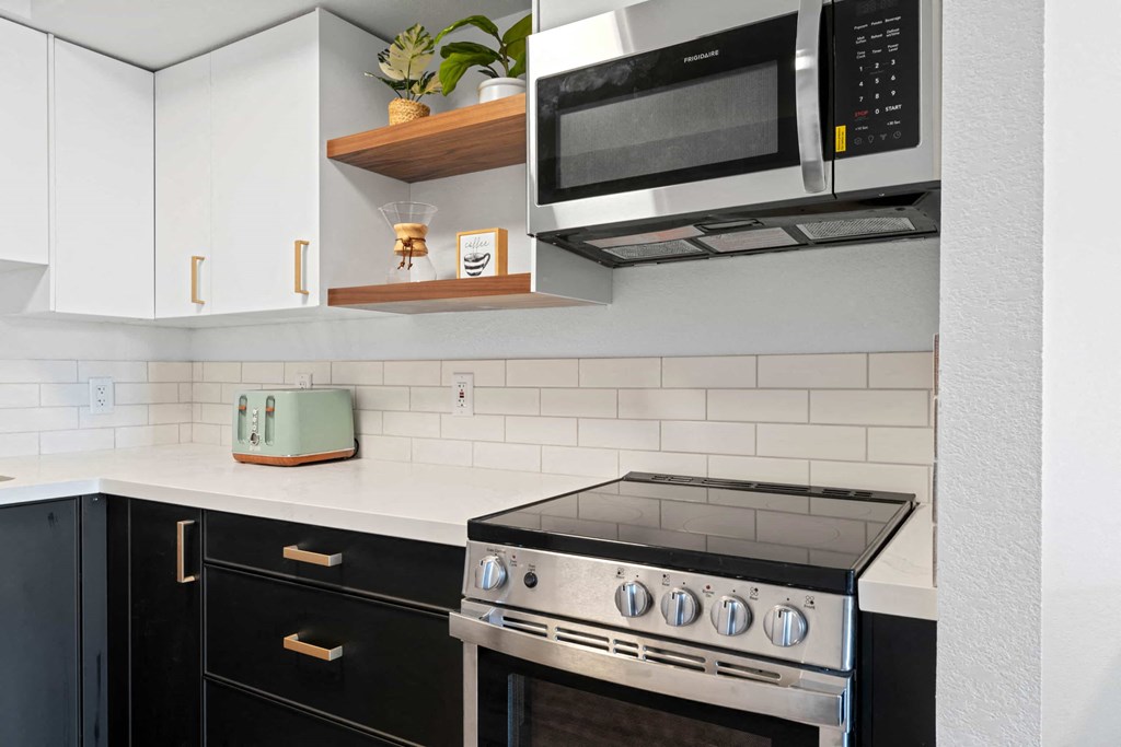 a kitchen with black cabinets and a stove and a microwave