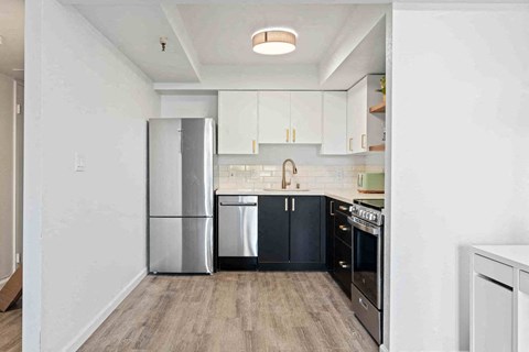 a kitchen with black and white cabinets and a refrigerator
