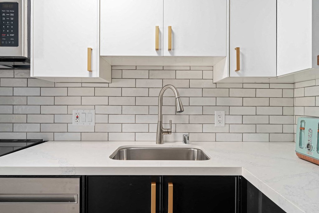 a clean kitchen with white cabinets and a sink
