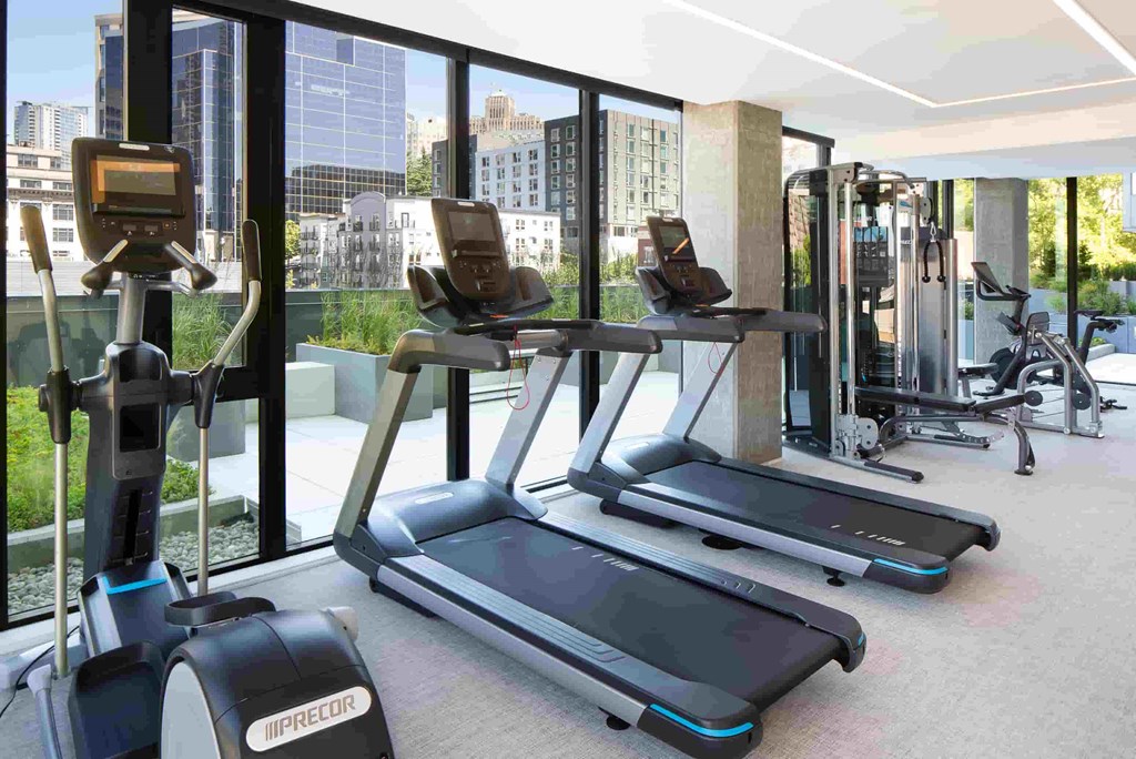 a gym with cardio equipment and a view of the city