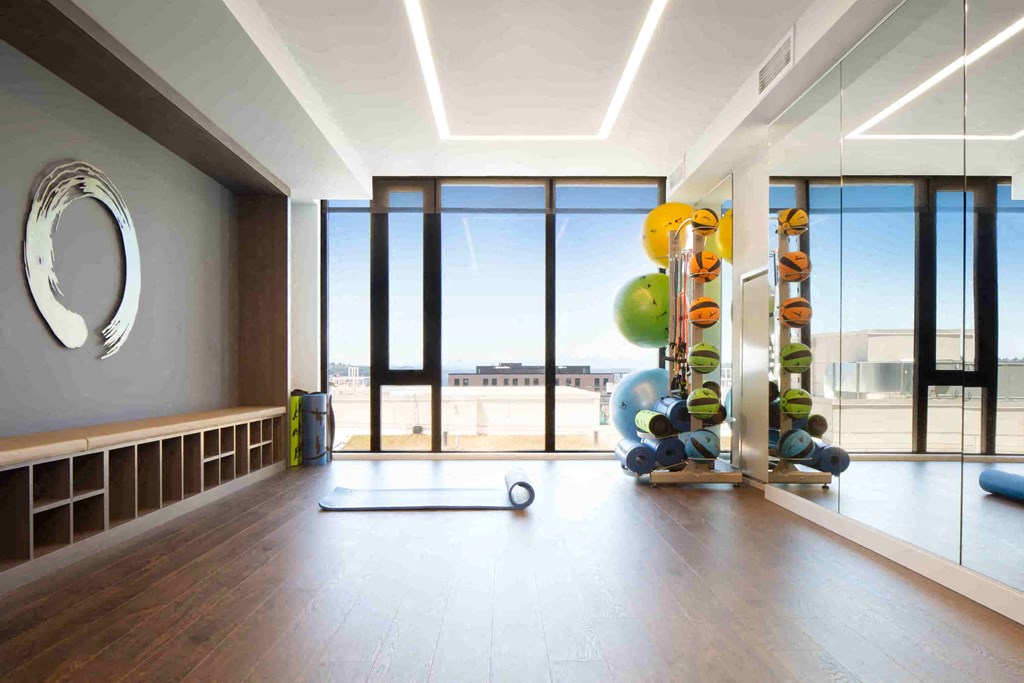 a workout room with weights and other exercise equipment in a building with large windows