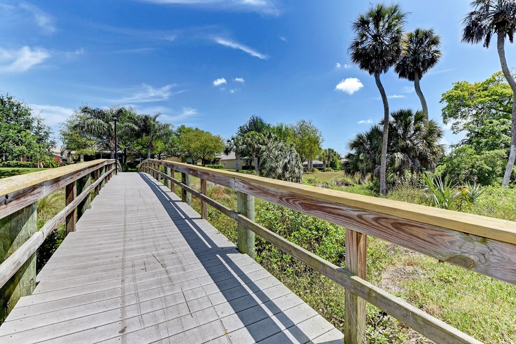 a wooden bridge in a park with palm trees