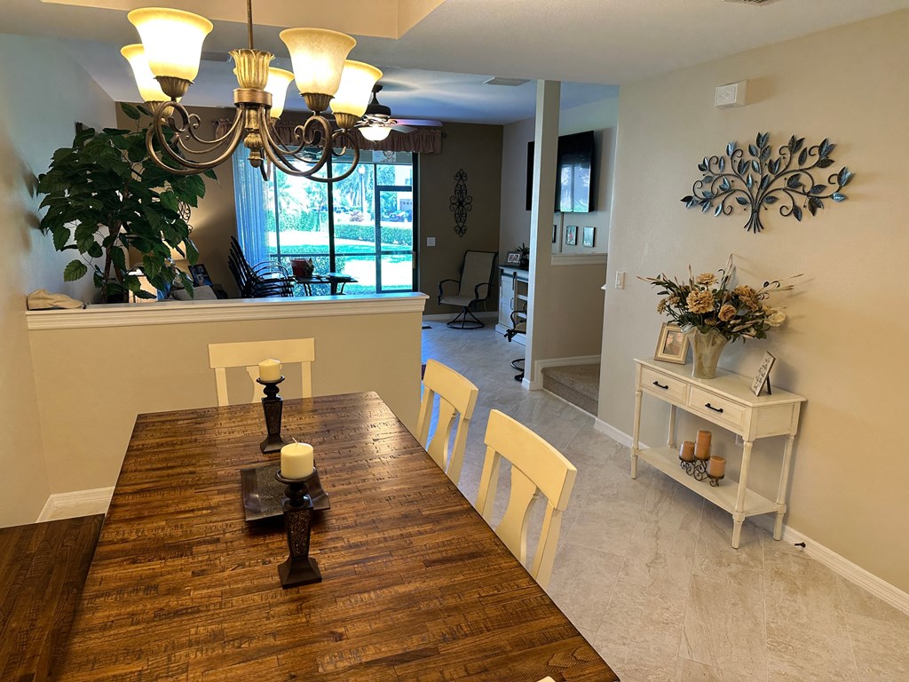 a dining room and living room with a wooden table and a chandelier