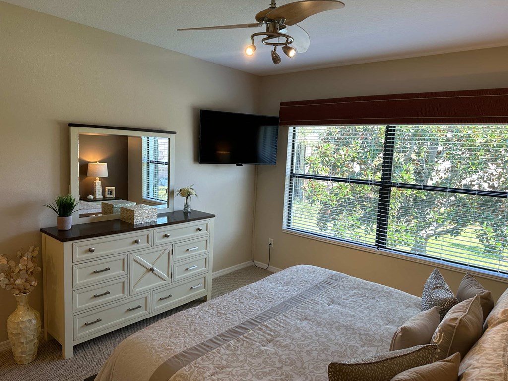 the master bedroom has a large window and a dresser with a tv