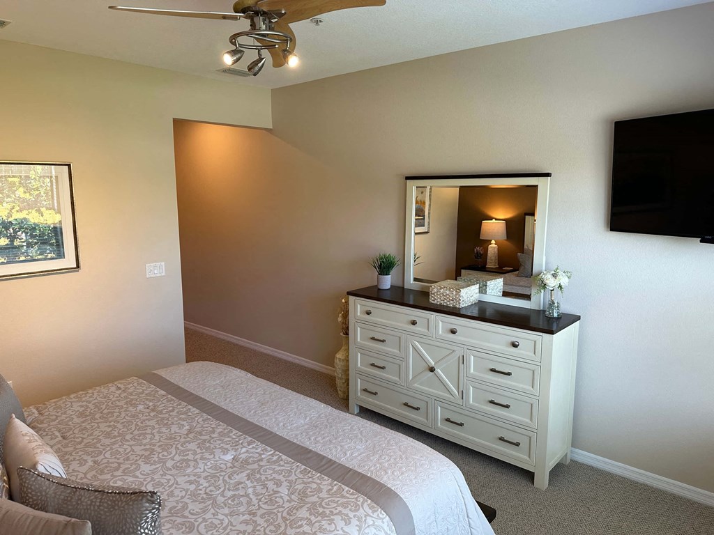 a bedroom with a bed and a dresser with a mirror