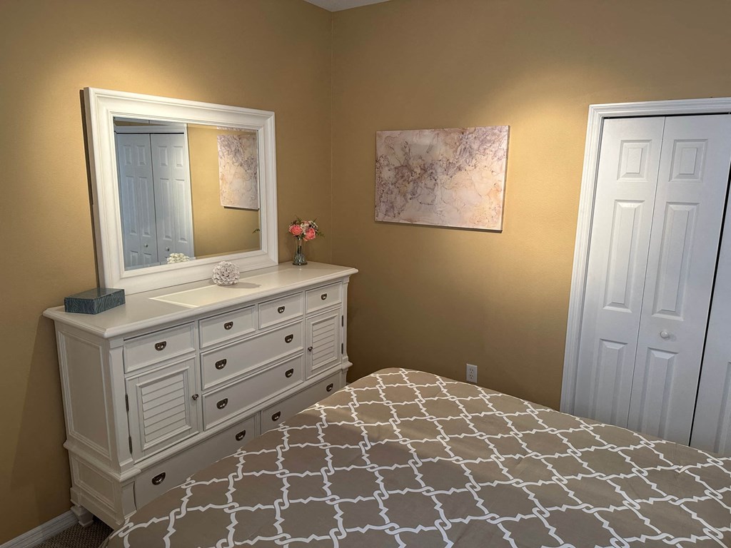 a white dresser with a mirror and a bed
