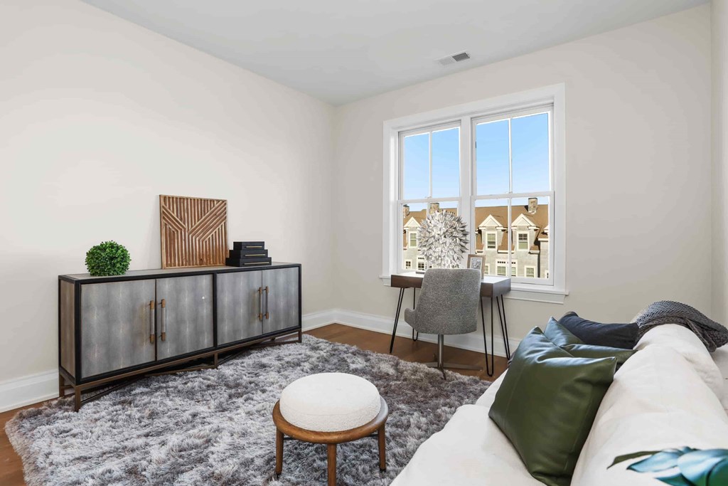 A living room with a white couch, a grey chair, a glass cabinet, and a small table.