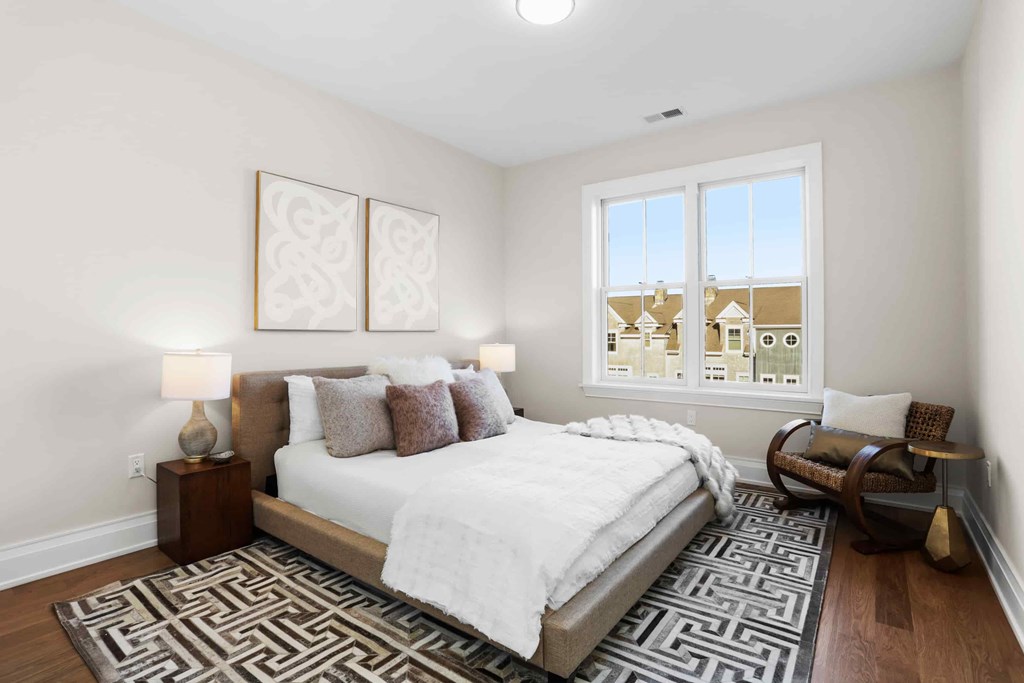 A bedroom with a large bed and a window overlooking a cityscape.