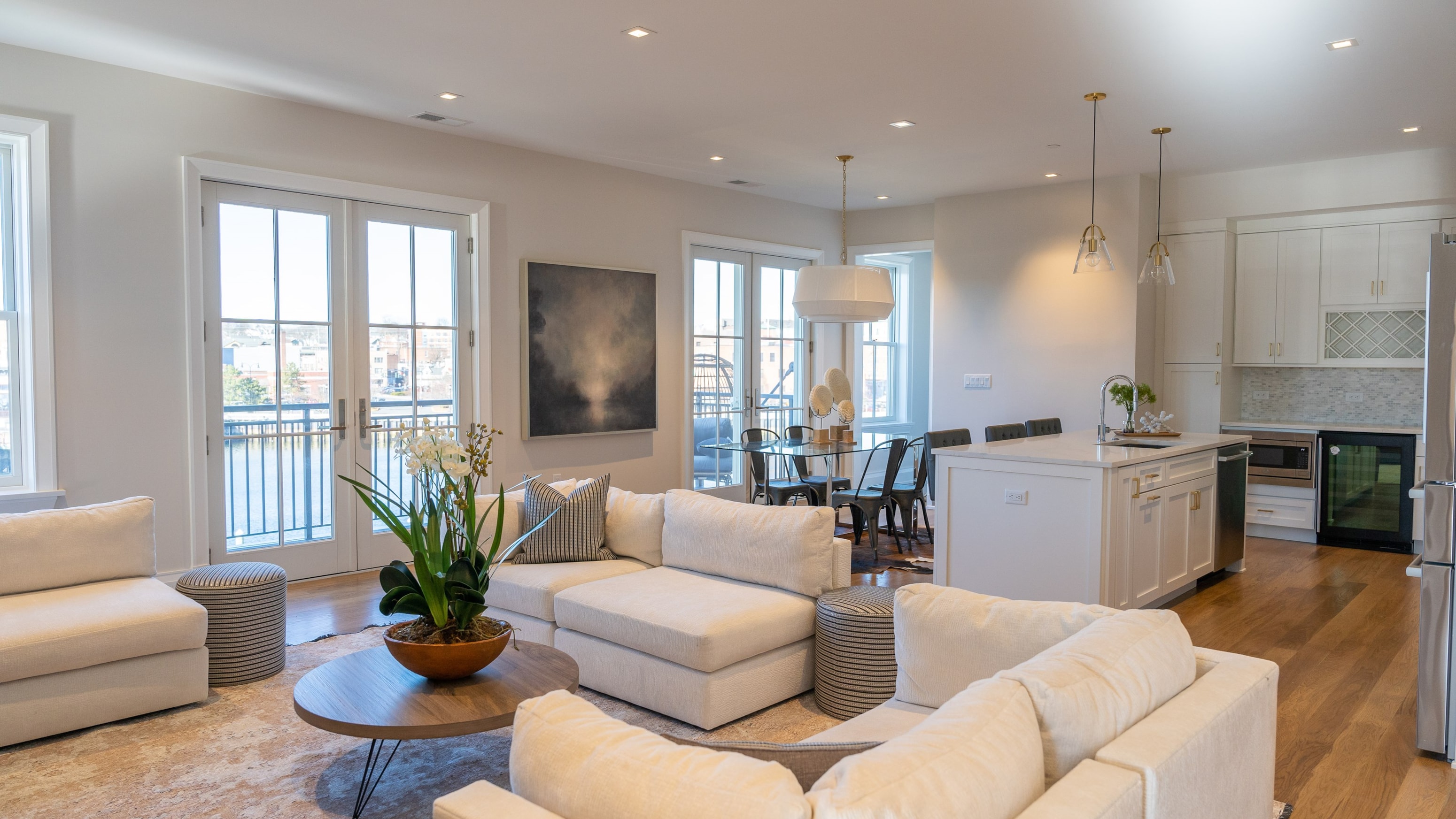 A modern living room with white furniture and a large window.