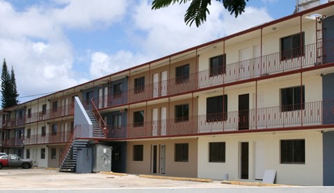 the outside of a building with balconies and a car parked in front