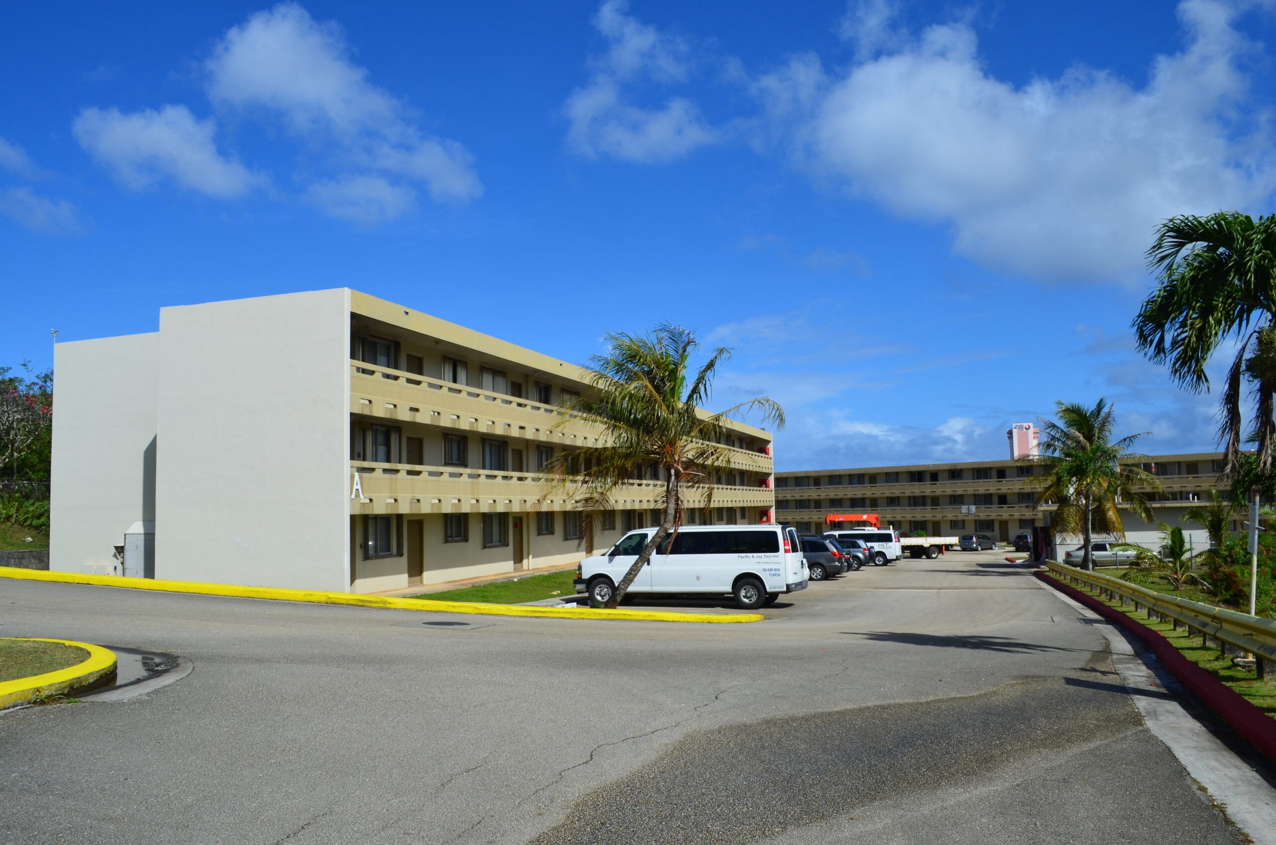 a building with cars parked in front of it and palm trees