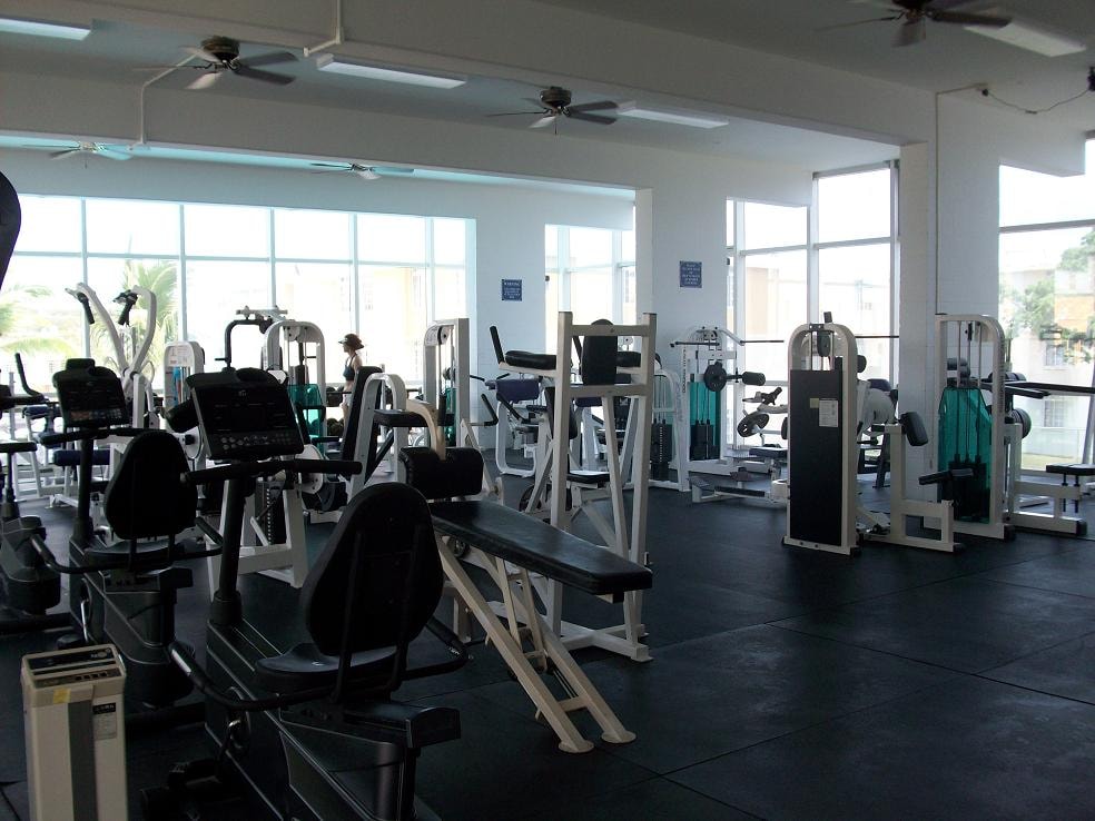A gym with a variety of equipment including treadmills, weights, and exercise machines.