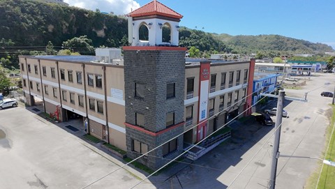 A large building with a tower has a red roof and is surrounded by other buildings.