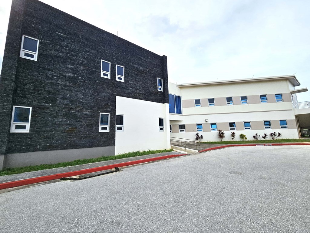 A black building with white windows is adjacent to a white building with blue trim.