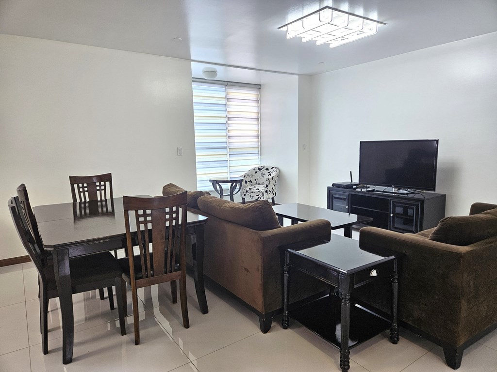 A living room with a brown couch, a black table, and a television.