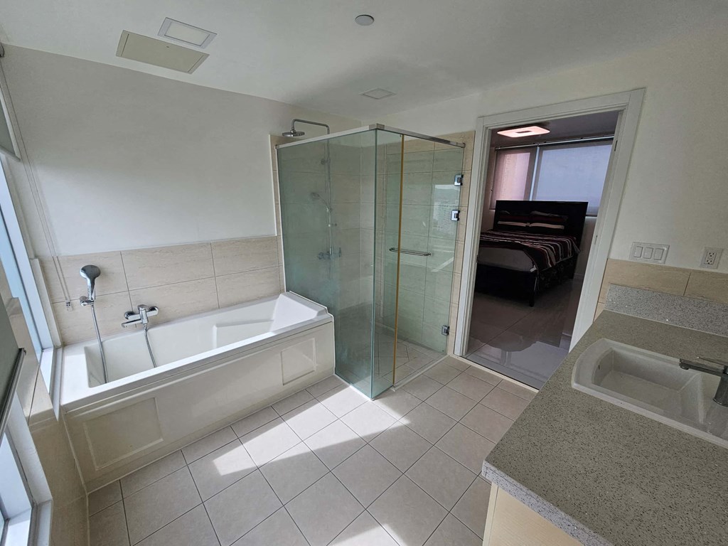 A bathroom with a glass shower door and a white bathtub.
