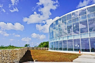 a large glass building with a blue sky and clouds